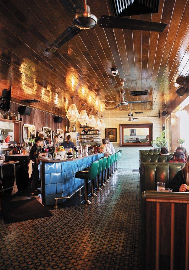 Interior of Little Nickel restaurant with a long bar and warm wood ceiling